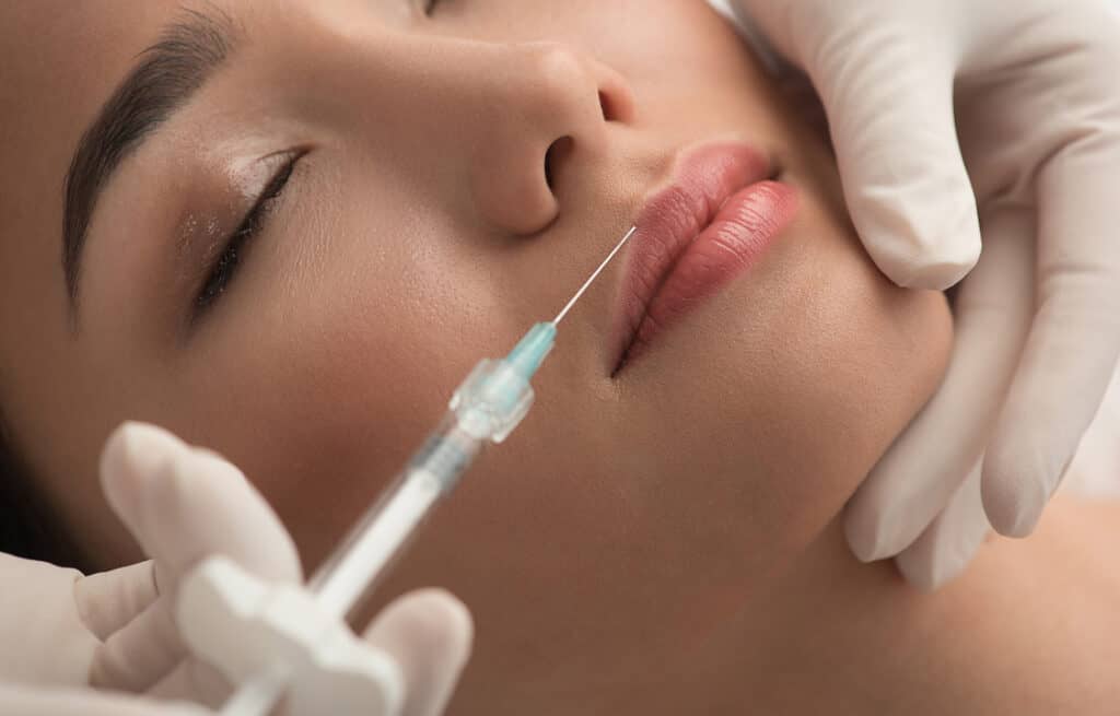A close-up of a woman receiving a lip injection.