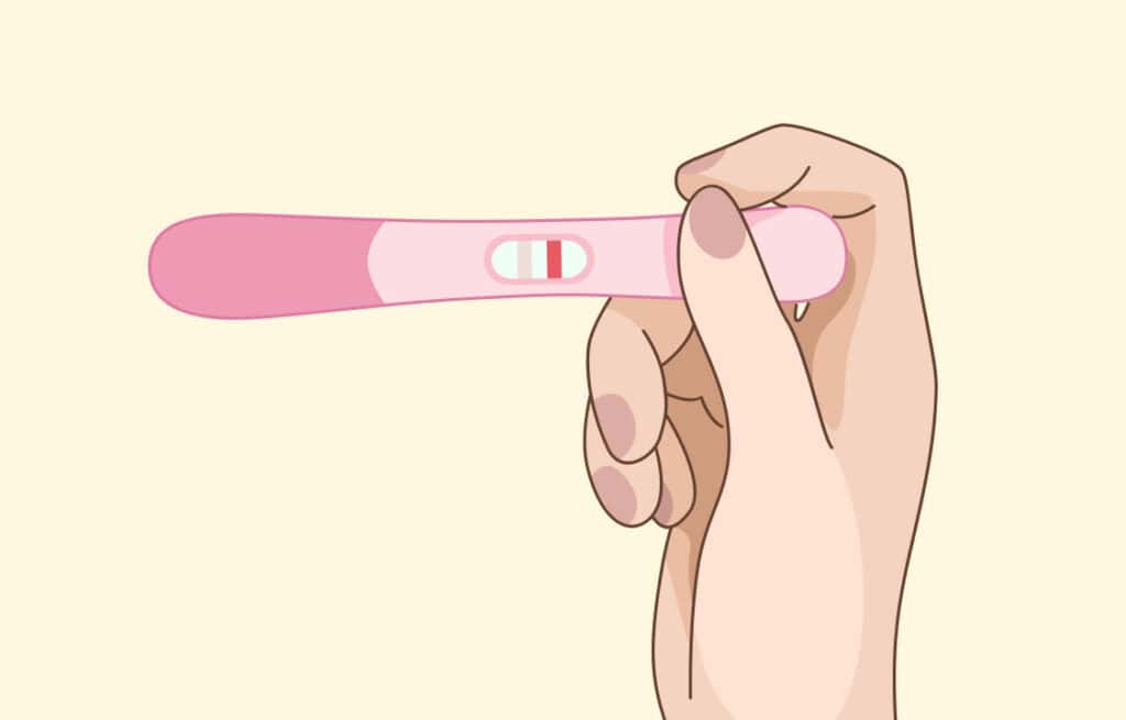 A hand holding a pregnancy test with two pink lines, one of them faint, indicating a positive result.