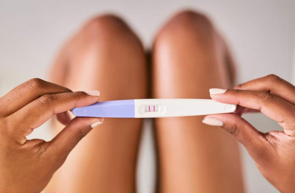 Close-up of hands holding a positive pregnancy test.