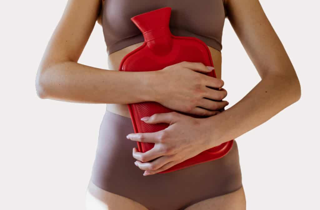 Woman holding a hot water bottle against her belly, symbolizing endometriosis self-care.