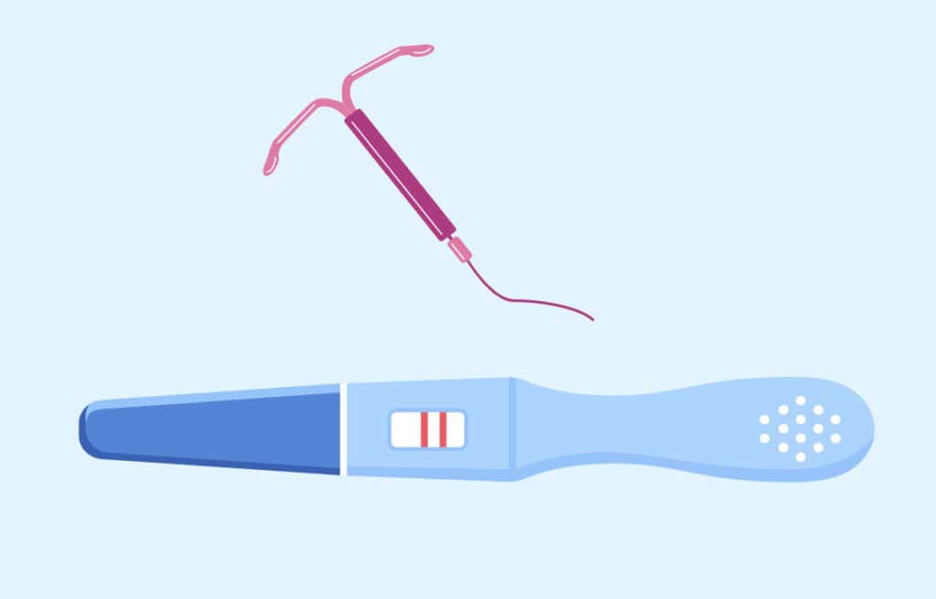 An IUD next to a positive pregnancy test, illustrating the concept of getting pregnant after IUD removal.