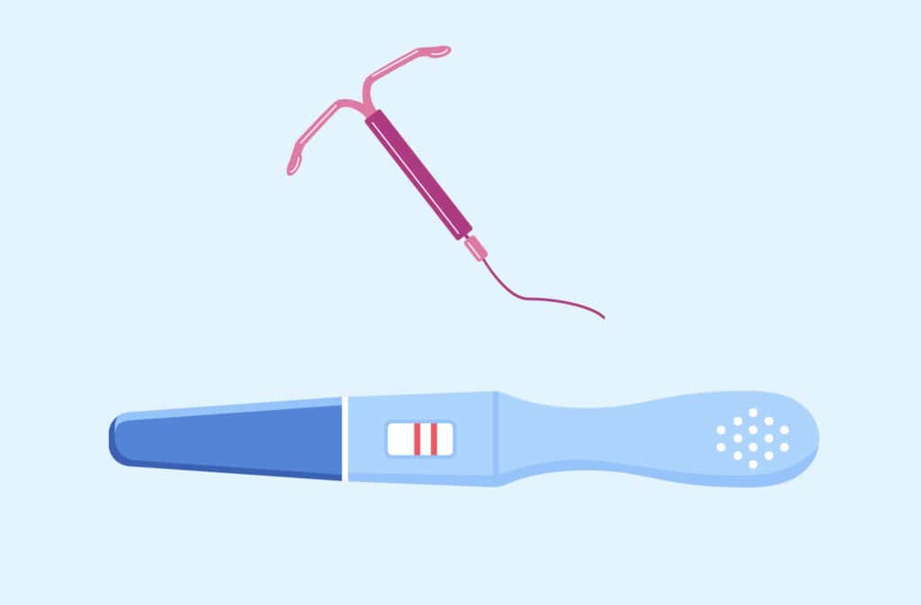 An IUD next to a positive pregnancy test, illustrating the concept of getting pregnant after IUD removal.