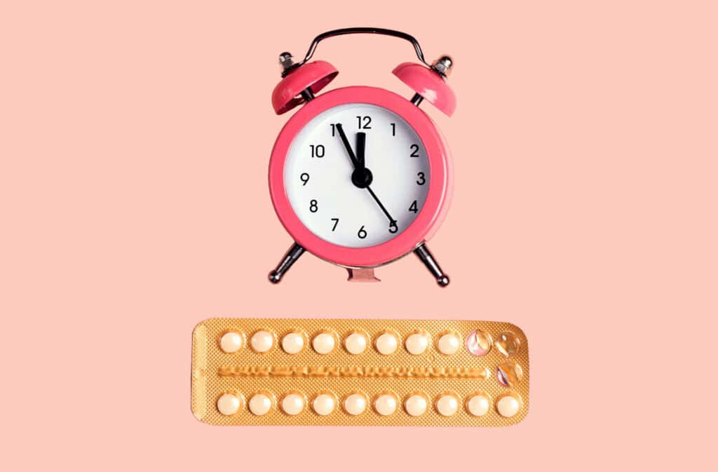 An alarm clock above a blister pack of birth control pills.