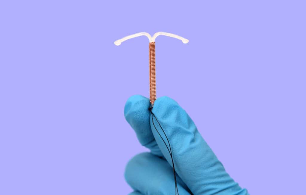 A hand holding an intrauterine device (IUD).