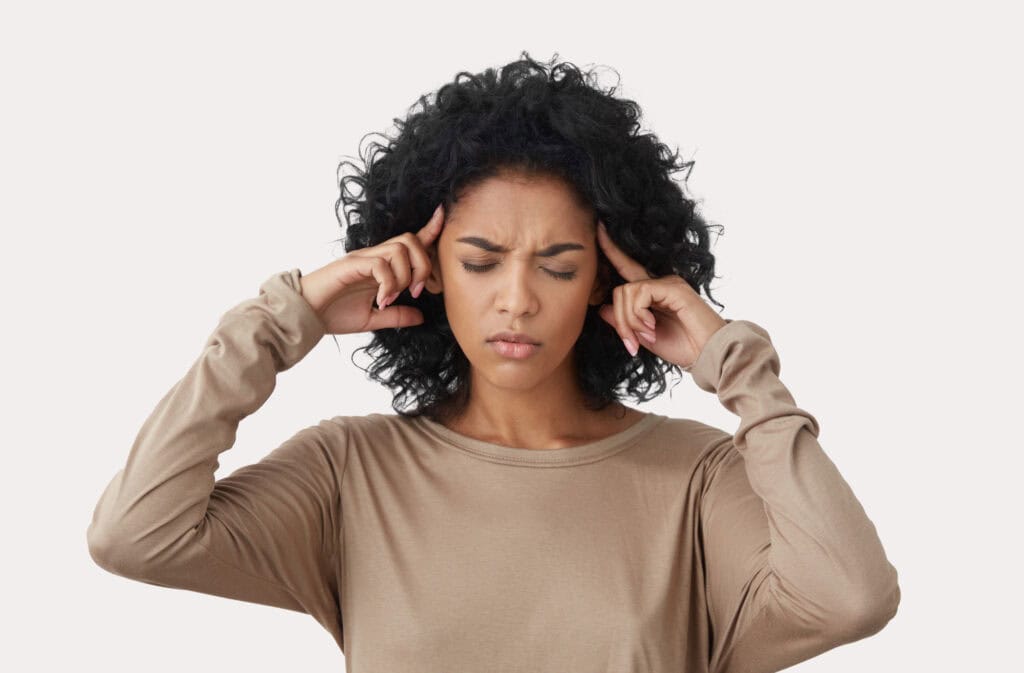 An image of a woman of color holding her head representing postpartum dizziness.