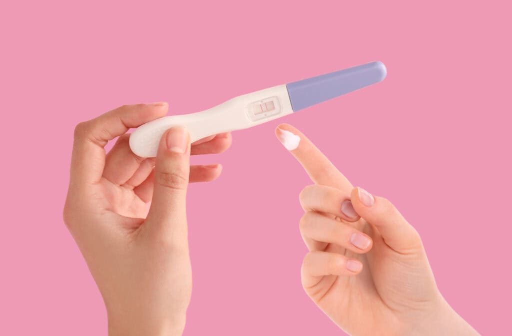 A photo of hands with white discharge and a positive pregnancy test, illustrating the discharge after ovulation: could it be a sign of pregnancy.