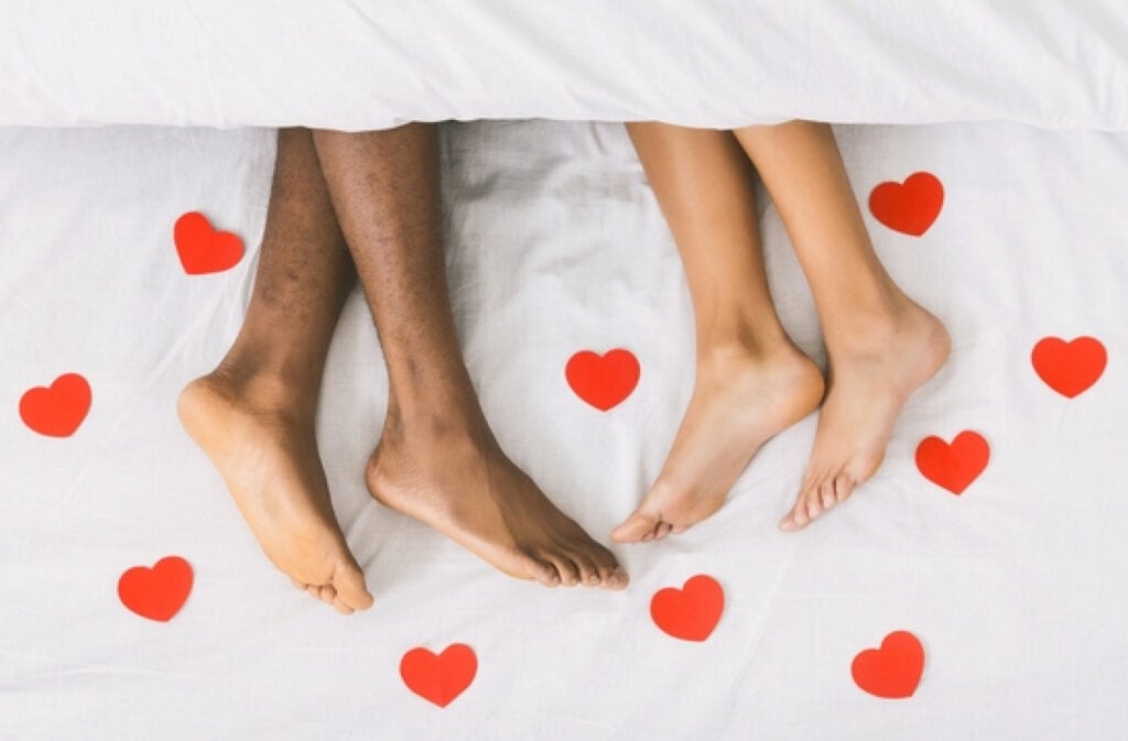 A photo of two pares of being in bed surrounded by red hurts, representing bleeding during sex.