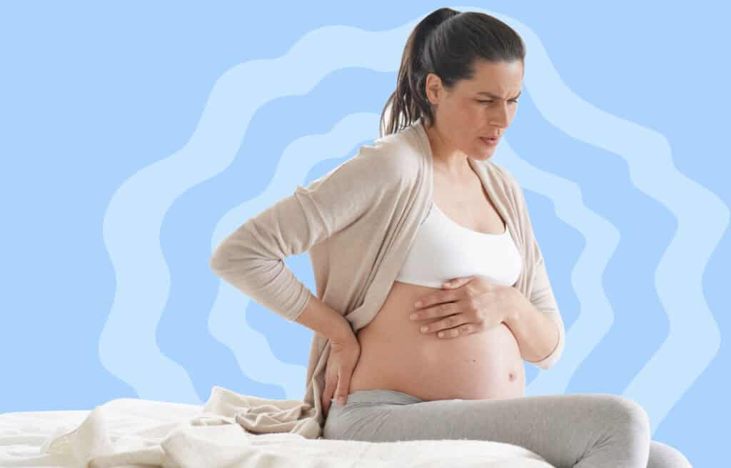 A photo of a pregnant woman holding her belly while experiencing a spasm, representing Braxton Hicks vs contractions.