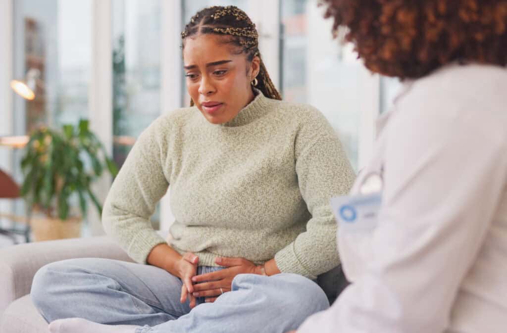 A photo of a woman at the doctor's appointment touching her belly with both hands, probably because of a missed miscarriage.