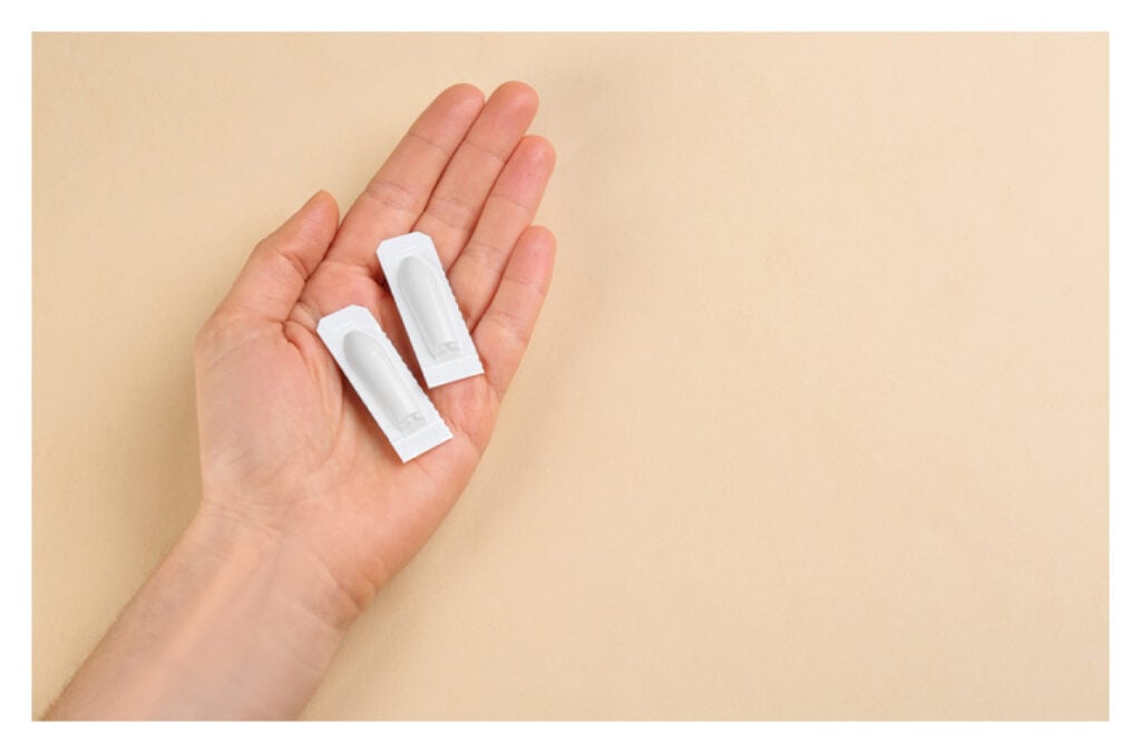 A photo of a hand holding two of progesterone suppository.