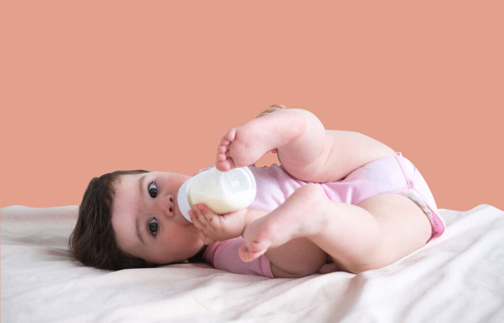 A photo of a baby sucking a bottle, representing a milk tongue in babies.