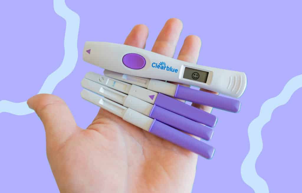 A photo of a hand holding a bunch of ovulation tests, representing signs.